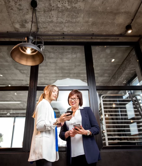 Two female social workers in an office looking at a mobile phone